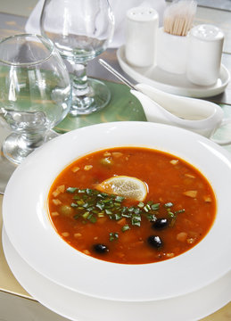 Fresh soup with herbs and olives on the served table