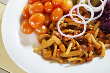 Pickled small tomatoes with rings of onion and mushrooms
