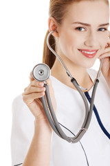 Young caucasian nurse or doctor is listening through stethoscope