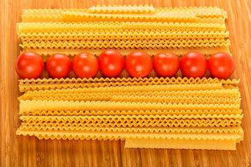 Italian pasta spaghetti and cherry tomato isolated on wooden bac