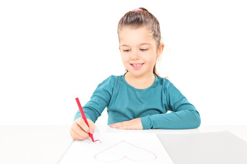 Little girl drawing hearts to a blank piece of paper