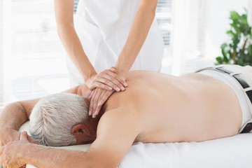 Therapist massaging back of senior patient