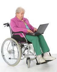 Fototapeta na wymiar Seniorin im Rollstuhl benutzt einen Computer