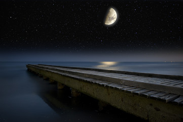 The Moon and stars above a wooden pier. © marcel