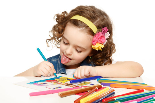 Cheerful little girl with felt-tip pen drawing in kindergarten