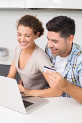 Happy couple using laptop together to shop online