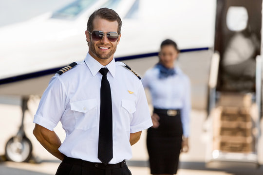 Pilot Standing With Stewardess And Private Jet At Terminal