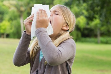 Fototapeta premium Girl sneezing into tissue paper at park