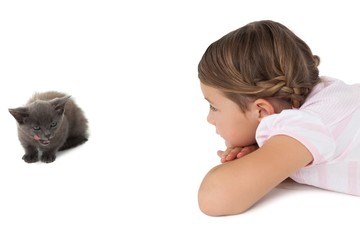 Fototapeta na wymiar Cute girl looking at grey kitten lying on floor
