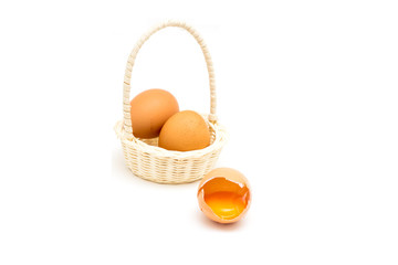 With brown eggs in basket  . One egg is broken.