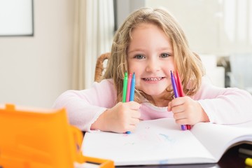 Cheerful little girl colouring at the table - obrazy, fototapety, plakaty