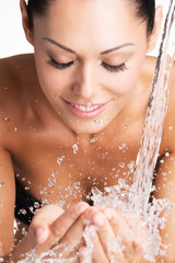 smiling woman washing her face with water