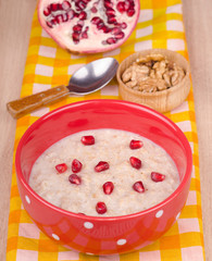 Oatmeal with garnet and walnut in bowl on table close-up
