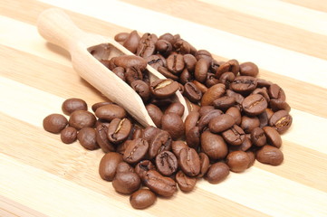 Heap of coffee on wooden spoon. Wooden background