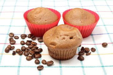 Fresh baked muffins and coffee grains on colorful cloth