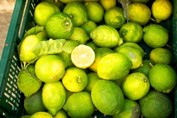 Green lime fruits in plastic box for sale.