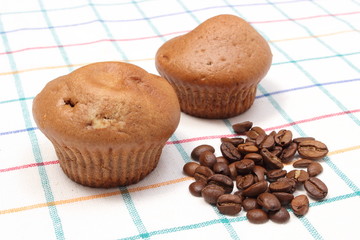 Fresh baked muffins and coffee grains on colorful cloth