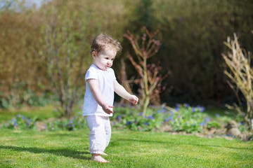 Funny baby girl making her first steps in the garden