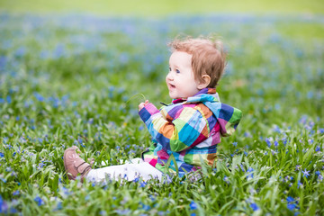 Beautiful little girl playing among first blue flowers