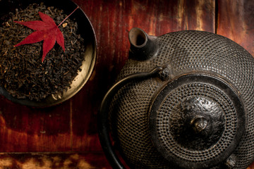 Naklejka premium Japanese iron teapot and heap of tea leaves from top.