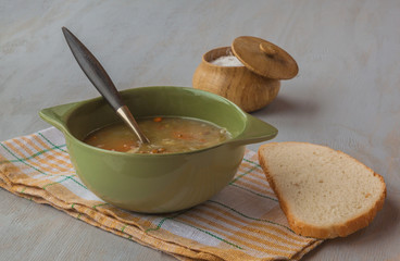 A bowl of lentil soup with a bread and salt