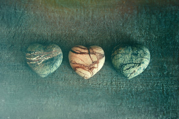 Three stone hearts on wood