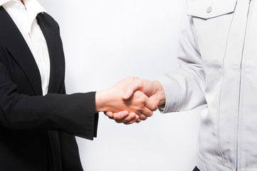 握手するスーツの女性と作業服の男性