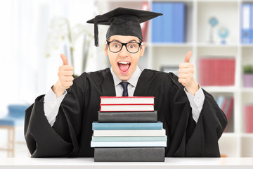Excited student giving thumbs up behind stack of books