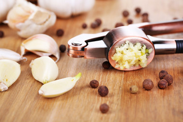 Garlic press on wooden background