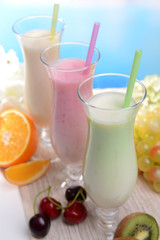 Milk shakes with fruits on table on light blue background