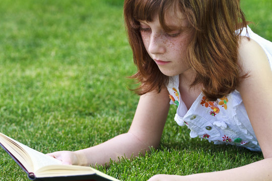 Books.Young beautiful girl reading a book outdoor