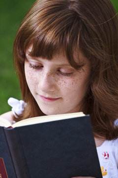 Relaxation.Young beautiful girl reading a book outdoor