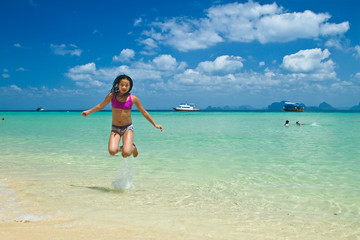 Girl jumping in the water at the beach of the Koh Ngai island Th