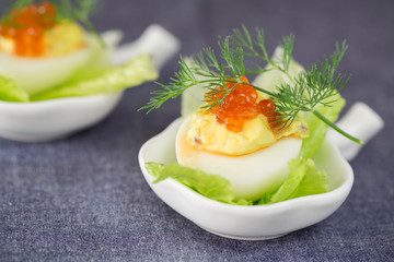 Staffed egg appetizer with red caviar garnish and dill decoratio