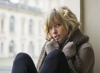 Attractive blonde young woman sitting next to window