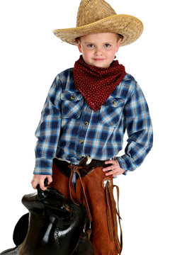 adorable young cowboy hands on hip holding saddle