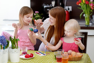 Mother and her daughters painting Easter eggs
