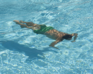 Man swimming underwater in pool