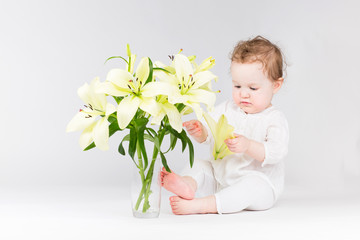 Funny little baby playing with lily flowers