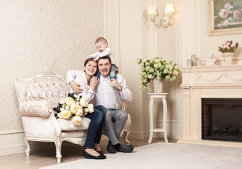 Obraz premium Young happy family with a baby indoors