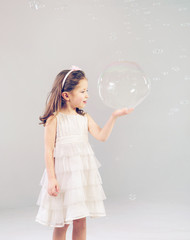 Funny lovely little girl playing with soap bubbles