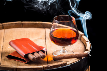 Cognac in a glass on barrel and burning cigar