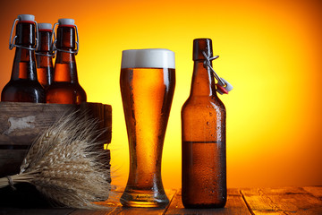 Beer glass and bottle with vintage crate and wheat bunch