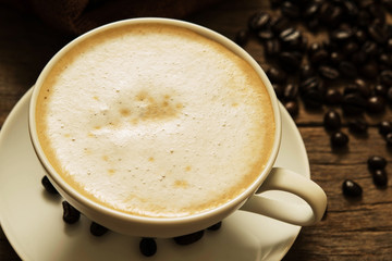 Coffee with roasted coffee beans on old wooden background.