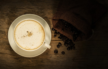 Coffee with roasted coffee beans on old wooden background.