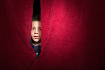 Child appearing beneath the curtain - obrazy, fototapety, plakaty