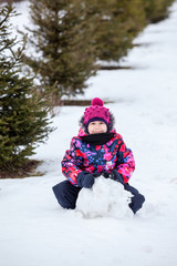 Girl making snowball for a snowman at winter