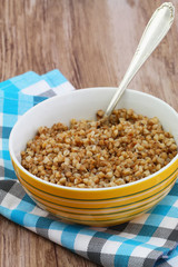Cooked buckwheat in bowl on checkered cloth