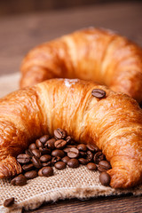 Two croissants and coffee beans on a linen napkin