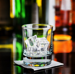 Glass with ice cubes on a bar desk